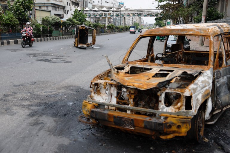 A man rides his motorcycle past wrecked cars